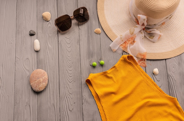 roupa de praia laranja mulher top outfit chapéu bolsa proteção solar óculos de sol seixos. fundo de verão