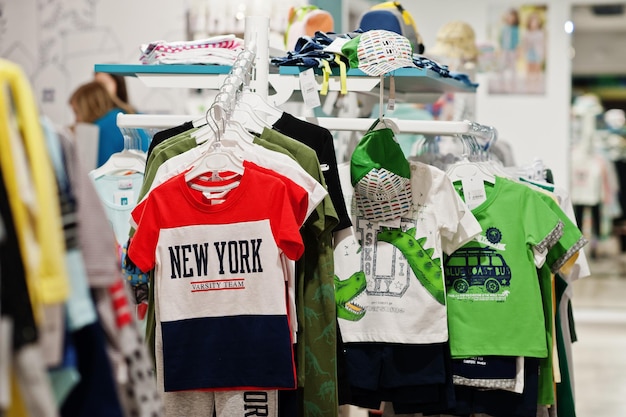 Foto roupas brilhantes para crianças penduradas na vitrine na seção de meninos da loja de roupas para bebês