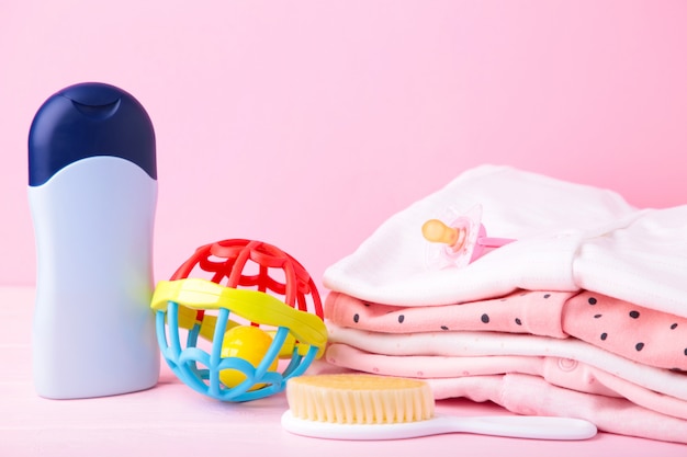 Roupas de bebê com acessórios de banho em um fundo rosa