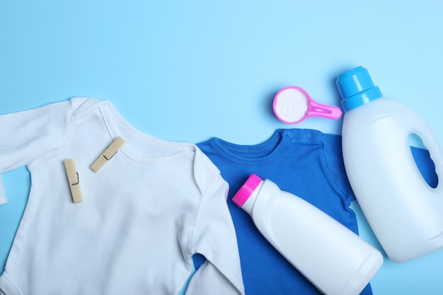 Roupas de bebê e detergentes em uma vista superior de fundo colorido