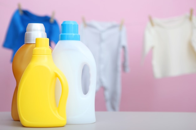 Roupas de bebê e detergentes na mesa conceito de cuidados com roupas de bebê