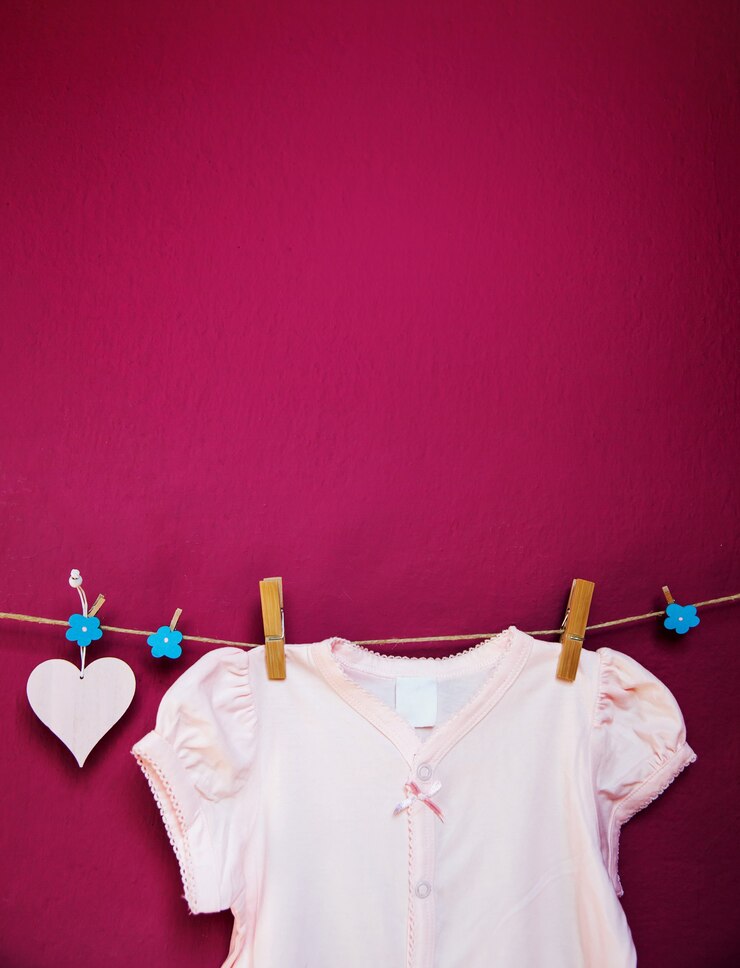 Foto roupas de bebê e mercadorias penduradas em prendedores de roupa no varal em um plano de fundo de parede texturizado