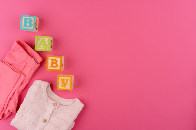 roupas de bebê na parede rosa vista superior