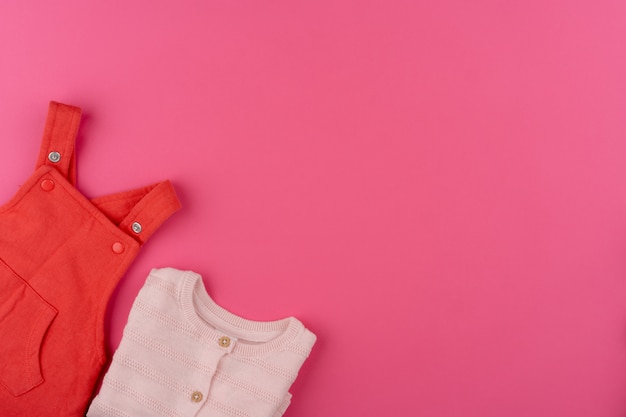 Foto roupas de bebê na superfície rosa