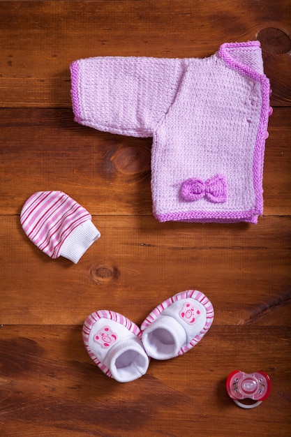 Roupas de bebê rosa camisola de malha luvas luvas e manequim na mesa de madeira