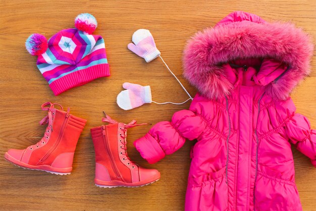 Foto roupas de inverno para crianças: casaco rosa quente, chapéu, luvas, botas. vista do topo.