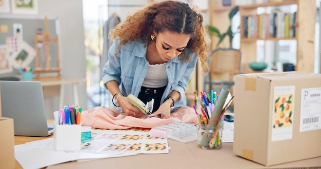 Roupas de pequenas empresas e uma mulher embalando um pedido ou logística para entrega de moda na loja Jovem empreendedor ou proprietário de empresa iniciante para pacote de comércio eletrônico ou embalagem de produto