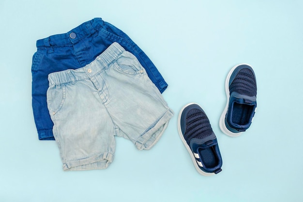 Foto roupas e acessórios azuis para bebês de verão com shorts jeans sapatilhas roupa infantil de moda modernaconjunto de roupas infantis para a primavera ou verão vista superior plana layoverheadmockup