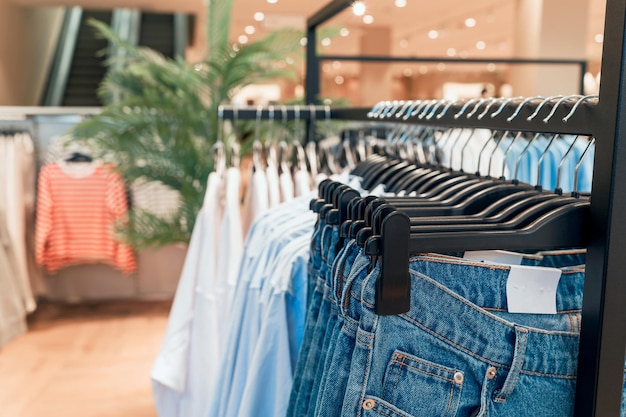 Foto roupas e jeans em cabides em uma loja de perto