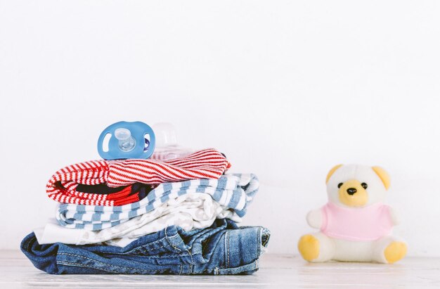 Foto roupas e ursinho de pelúcia na mesa contra fundo branco