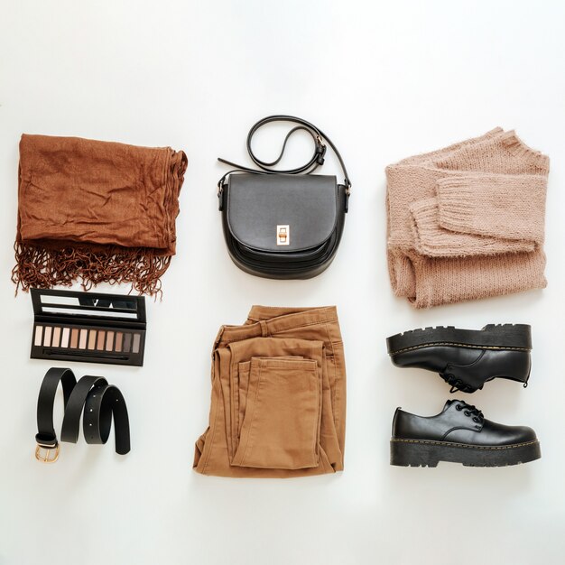Roupas femininas básicas da moda dobradas em conjunto com uma roupa de cor marrom bege. Liso plano quadrado