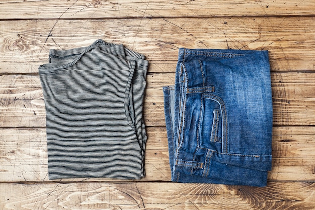 Roupas femininas de verão. Foto de moda plana leigos. T-shirt e calças de ganga listradas cinzentas no fundo de madeira.