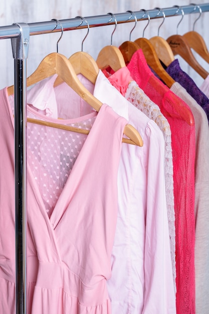 Roupas femininas rosa em cabides de madeira no rack em uma loja de moda. vestidos femininos de guarda roupa, blusas