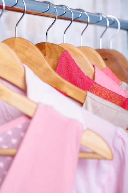 Roupas femininas rosa em cabides de madeira no rack em uma loja de moda. . vestidos femininos guarda-roupas, blusas fechadas