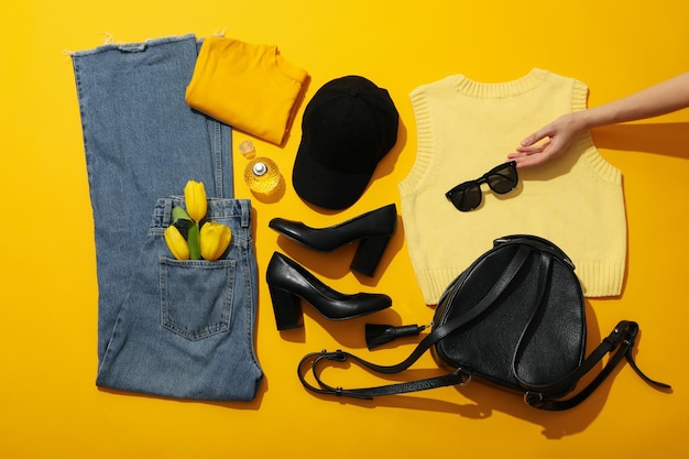 Roupas femininas sapatos acessórios e mão em fundo amarelo vista superior