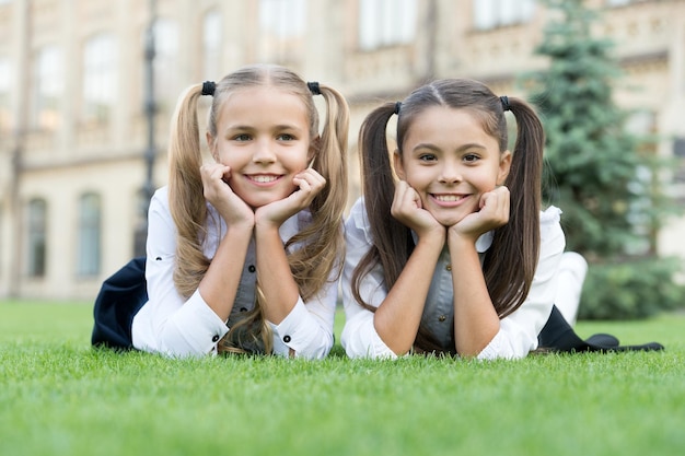 Roupas formais de amigos da escola relaxando no conceito futuro bem sucedido de grama verde