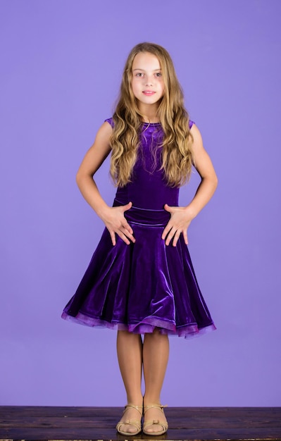 Roupas para dança de salão. O vestido da moda infantil parece adorável. Conceito de moda dancewear de salão de baile. Dançarina infantil satisfeita com a roupa do show. Moda infantil. Linda criança usar vestido violeta de veludo.