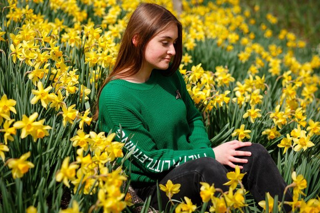 Foto roupas quentes em uma menina que coleta flores brilhantes em um vale de narcisos