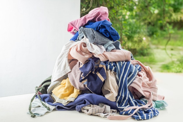 Roupas usadas em uma pilha Classificando e limpando de segunda mão Preparando para lavar Copie o espaço no fundo branco