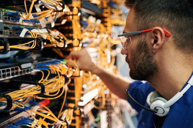 Foto routing de tecnologia moderna jovem está trabalhando com equipamentos de internet e fios na sala de servidores