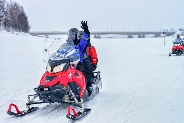 Rovaniemi, Finlândia - 2 de março de 2017: Pessoas andando de motos de neve e acenando com as mãos no lago congelado no inverno Rovaniemi, Lapônia, Finlândia do Norte