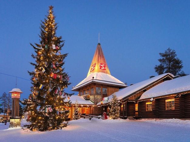 Rovaniemi, Finlandia - 5 de marzo de 2017: Oficina de Santa Claus en Santa Village con árboles de Navidad iluminados por la noche, Laponia, Finlandia, en el Círculo Polar Ártico en invierno.