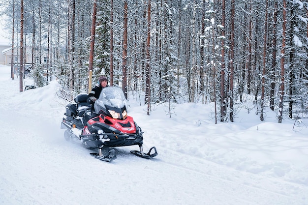 Rovaniemi, Finnland - 3. März 2017: Frau mit rotem Schneemobil im Winterwald in Rovaniemi, Lappland in Finnland