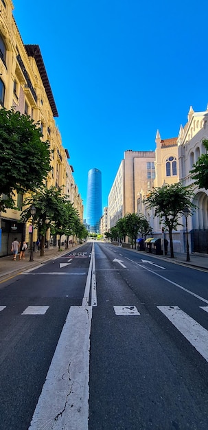 Rua de Bilbao sob o sol com a estrada vazia e a construção de vidro no fundo da imagem