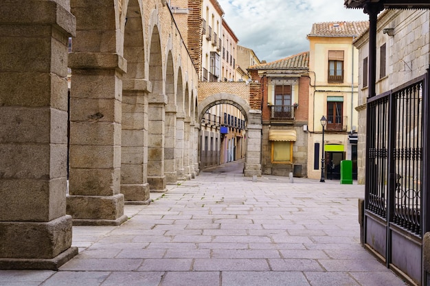 Rua e praça com arcos de pedra e casas antigas na cidade de Ávila, Espanha.