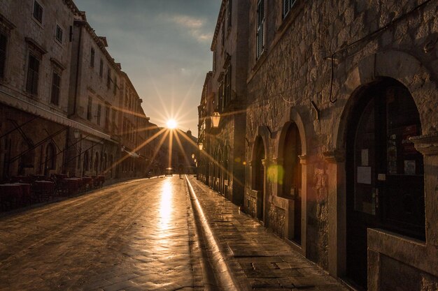 Foto rua em meio a edifícios contra o céu durante o pôr do sol