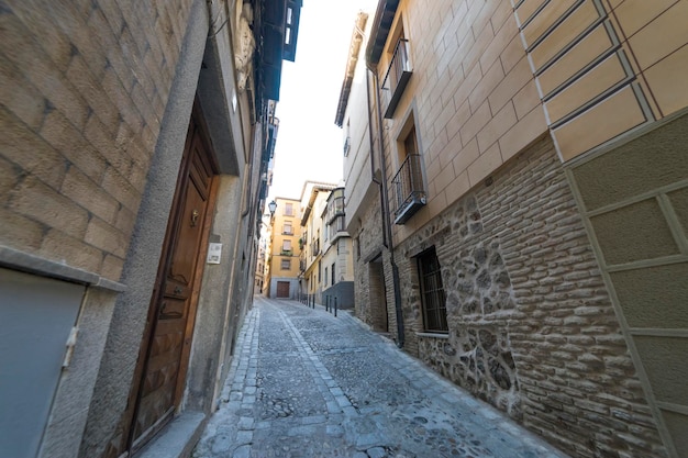 Rua medieval calcetada e escalonada com varandas floridas e candeeiros de iluminação pública na cidade de Toledo. Espanha