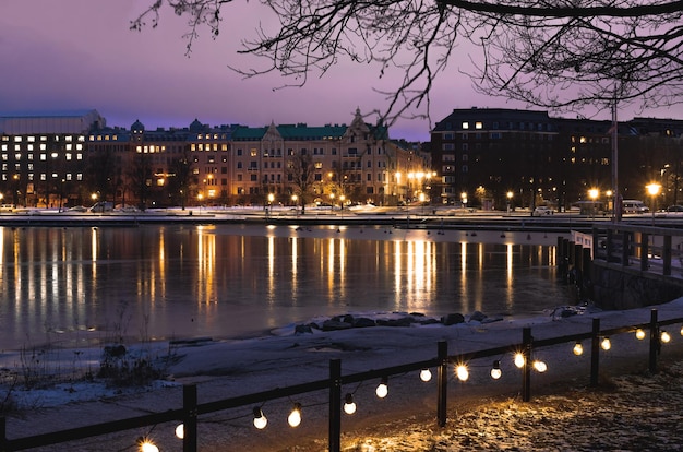 Rua noturna de Helsinque com luzes amarelas na margem da baía