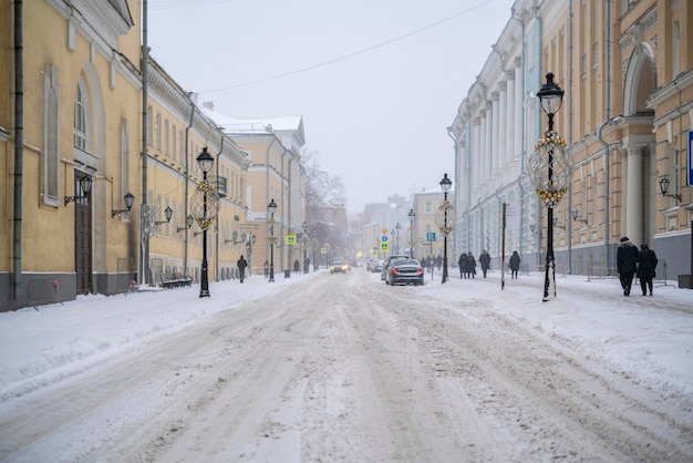 Rua secundária urbana. dia de nevoeiro. queda de neve na rua lateral deserta na cidade de inverno f