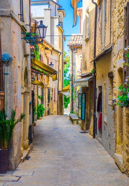 Rua típica italiana de paralelepípedos com edifícios tradicionais e casas com plantas verdes