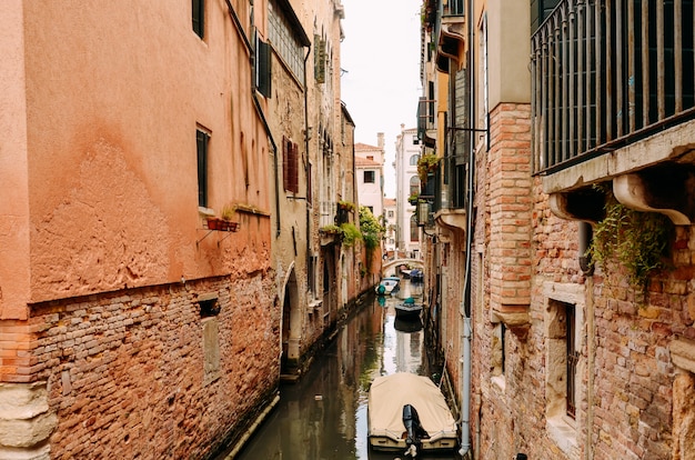 Rua tradicional do canal com a gôndola em Veneza, Itália. Canal estreito entre casas antigas de tijolos coloridos em Veneza, Itália