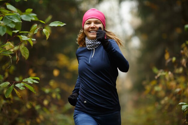 Rubia alegre corre por la mañana en el parque otoño