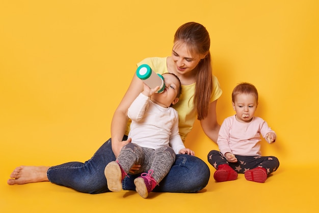 Rubia y amorosa madre cuida a sus pequeños hijos obedientes