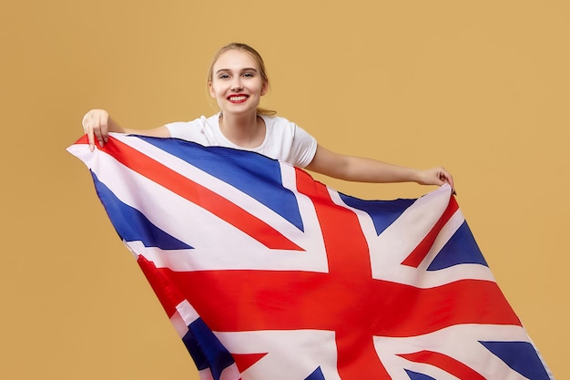 Rubia atractiva posa con una bandera británica. sesión de fotos en el estudio sobre un fondo amarillo.