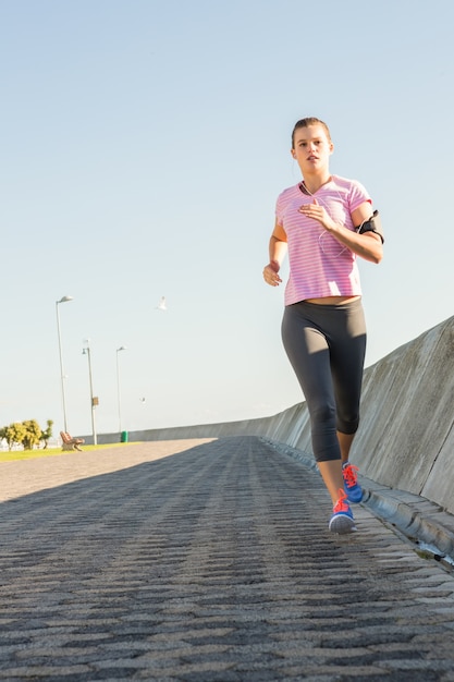 Rubia deportiva enfocada para correr en el paseo