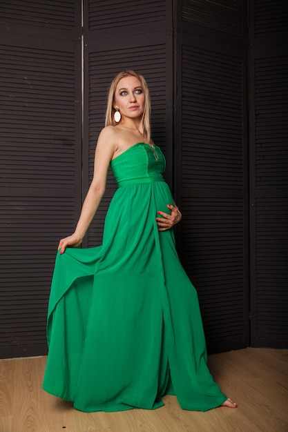 Foto rubia embarazada con vestido verde