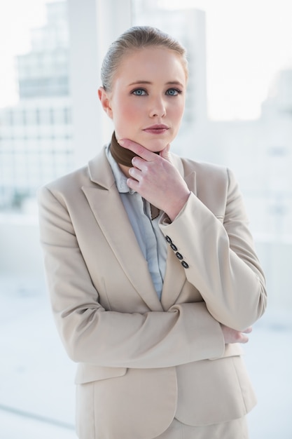 Rubia empresaria pensativa tocando su barbilla