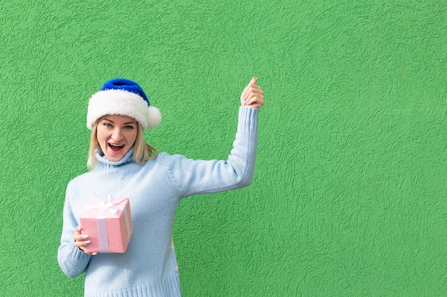 La rubia feliz con un sombrero de año nuevo con un regalo