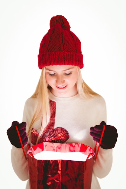 Rubia festiva abriendo una bolsa de regalo