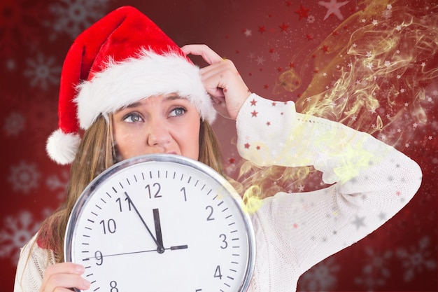 Rubia festiva mostrando un reloj contra el fondo borroso de Navidad