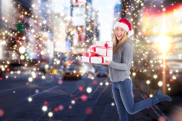 Rubia festiva sosteniendo un montón de regalos contra la calle borrosa de nueva york