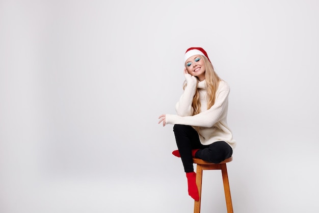 Rubia con un gorro de Papá Noel sobre un fondo gris. espacio libre para texto