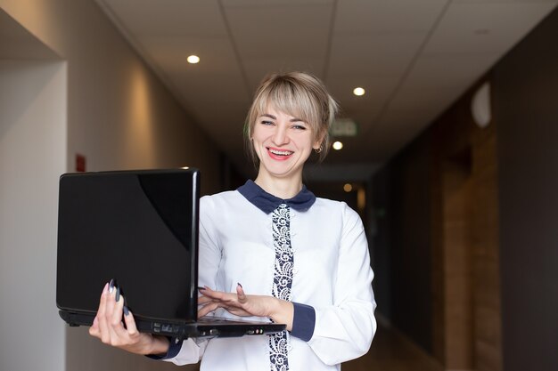 La rubia hermosa y feliz en manos de una computadora portátil