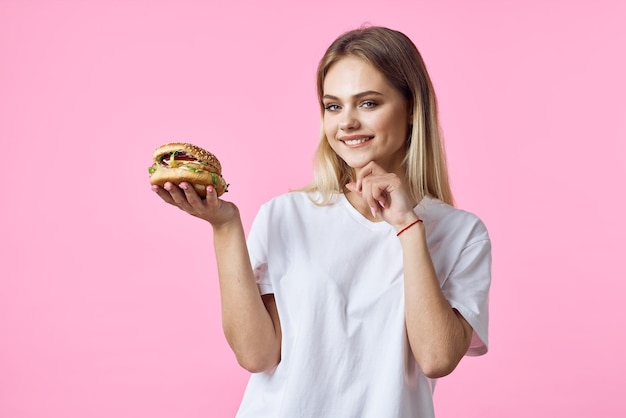 Una rubia linda con una camiseta blanca hamburguesa un restaurante de comida deliciosa