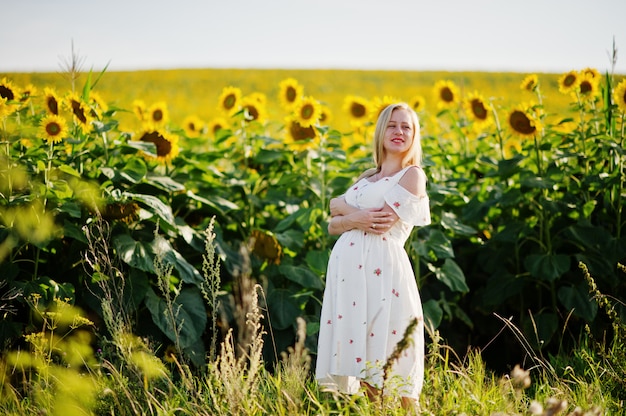 Rubia madre embarazada en el campo de girasoles. Momentos de embarazo