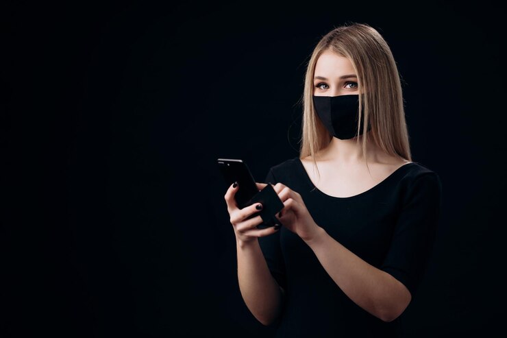 Rubia con máscara usando tarjeta de crédito y móvil para ir de compras